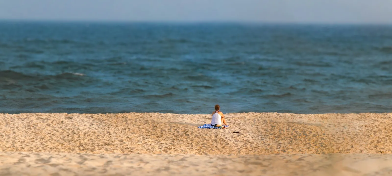 A lone woman stares out at the ocean while sitting on the beach - Web Design Southampton | Bloxli Web Design Southampton